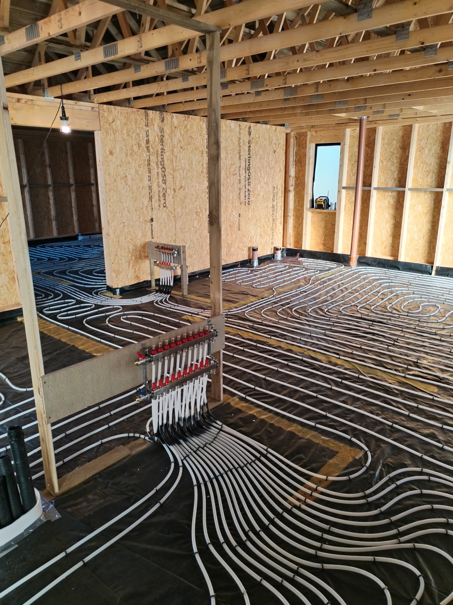 A large domestic underfloor heating installation with multiple Danfoss manifolds along with bend formers placed below the manifold to help protect the and prevent kinks in the pipes as they exit the floor to the manifold.