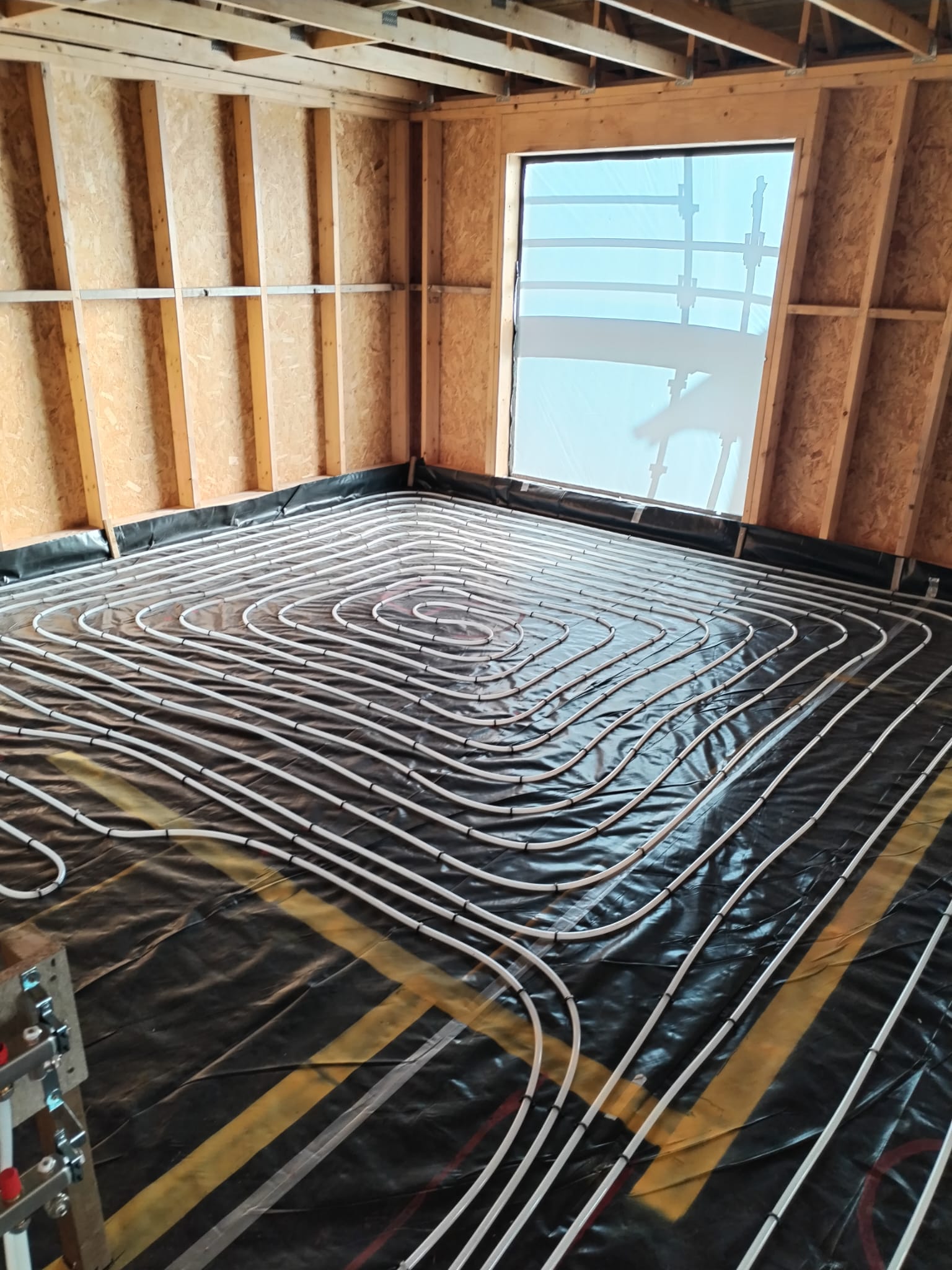 underfloor heating install using the Spiral pattern for the layout of the heating circuits. The pipes are stapled directly to the insulation which is covered by a membrane ready for the screed to be poured.